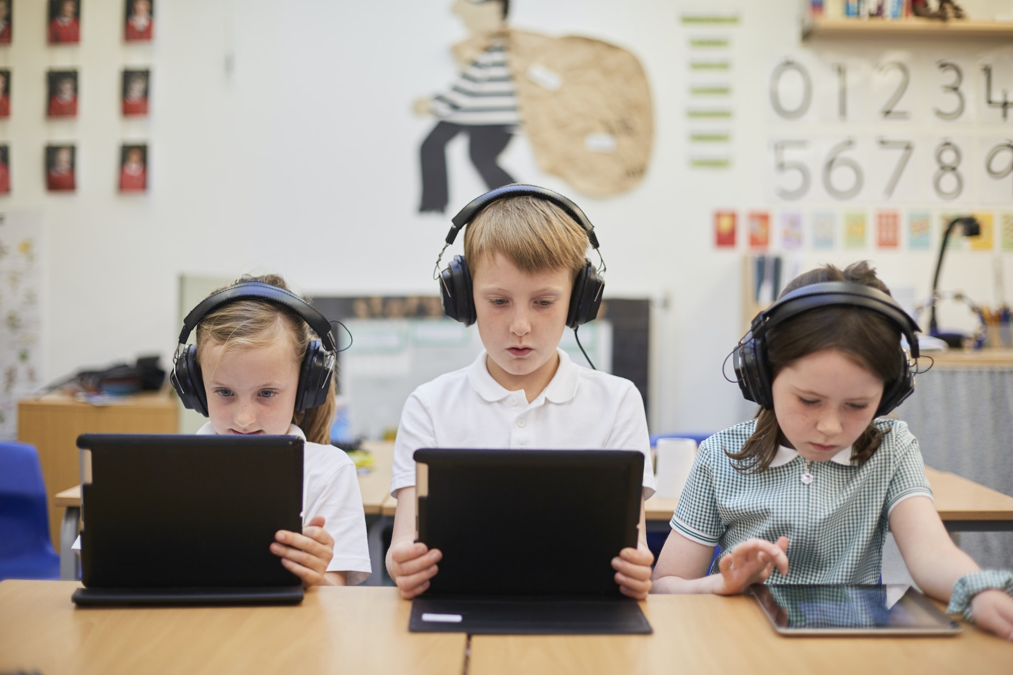 Schoolboy and girls listening to headphones in class at primary school