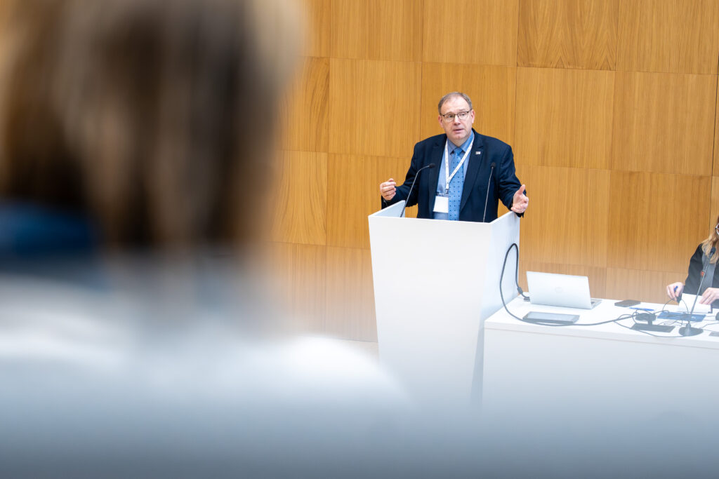 A speaker presenting at a seminar on teacher education standards, June 2026