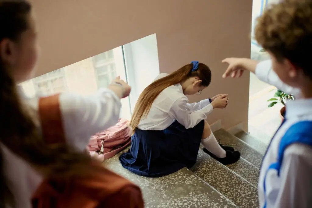 Illustration for the Don’t Look Away campaign: a student sitting alone on school stairs while peers look on